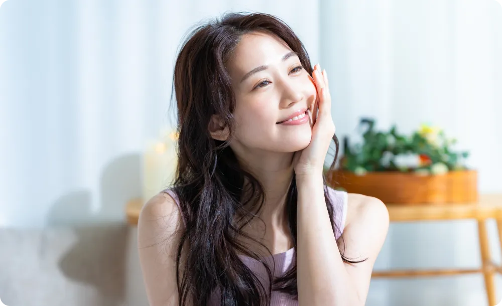 ほおに手を当てて微笑む女性